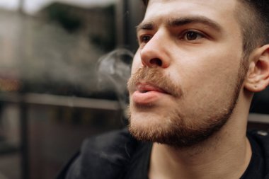 Adam sigara içiyor. Sigara dumanının yayılması. Bıyık