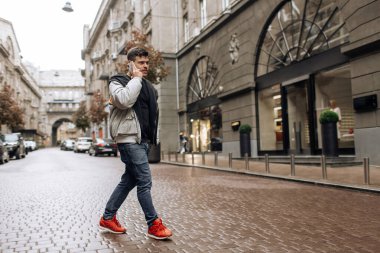 Sokakta yürüyen mutlu genç adamın portresi. Telefonuyla konuşurken yana bakıyor..