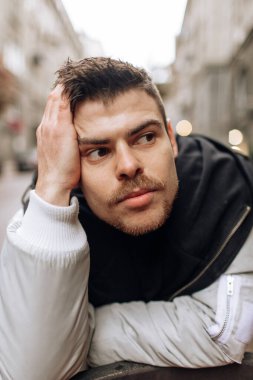 Şehirde dolaşan genç bir adamın portresi. Esmer, sakallı. Neşeli, güzel gülümseme.