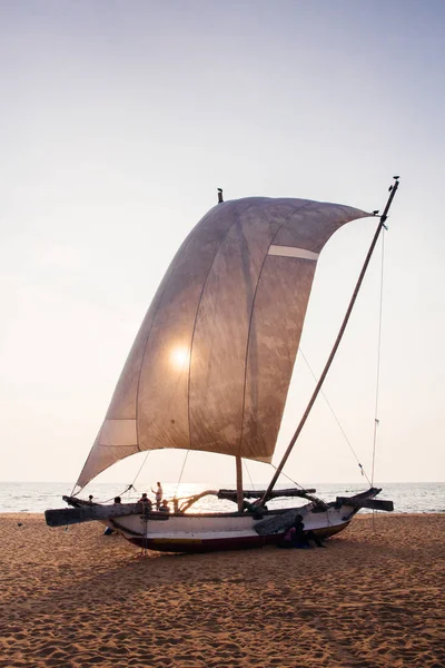 Традиционная рыболовная лодка на пляже Фатомбо, Шри-Ланка на закате Стоковое Изображение