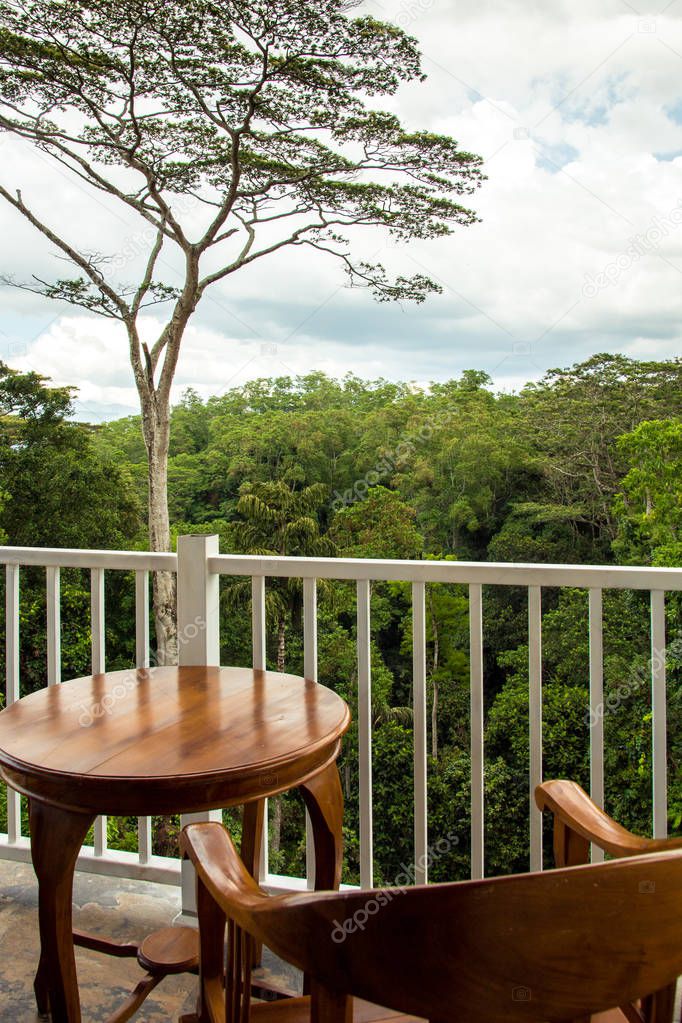 Wooden chair and table for 1 person in a balcony overlooking a f