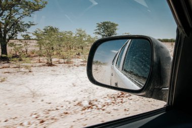 Etosha Ulusal Parkı Namibya 'daki kurak kurak arazide sürerken dikiz aynasına bak.