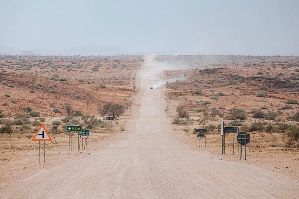 Cars kick up dust on the C35 gravel road in Tsiseb region, Namibia, Africa