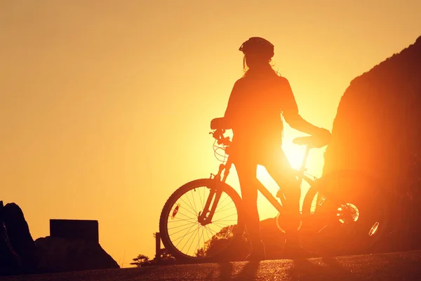 Silhouette of a young woman on a bicycle at sunset — Stock Photo, Image