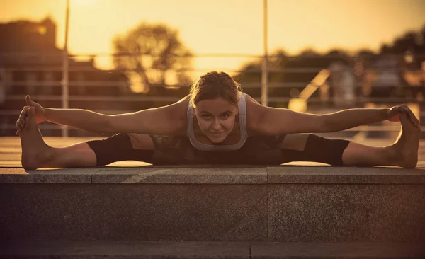 Giovane donna che pratica yoga, seduta in Samakonasana Posizione dritta in terrazza al tramonto — Foto Stock