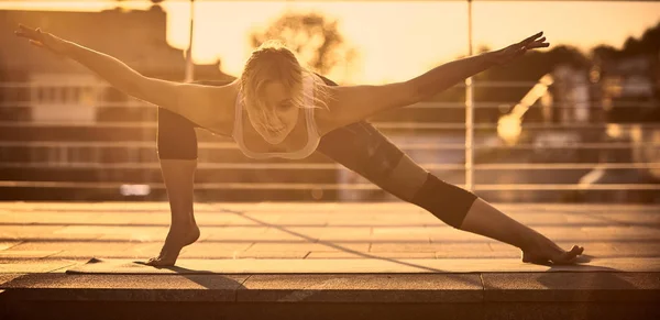 Krásná mladá žena praxe jógy na terase při západu slunce — Stock fotografie