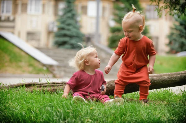 Jongetje en meisje van de baby spelen zittend op groen gras — Stockfoto