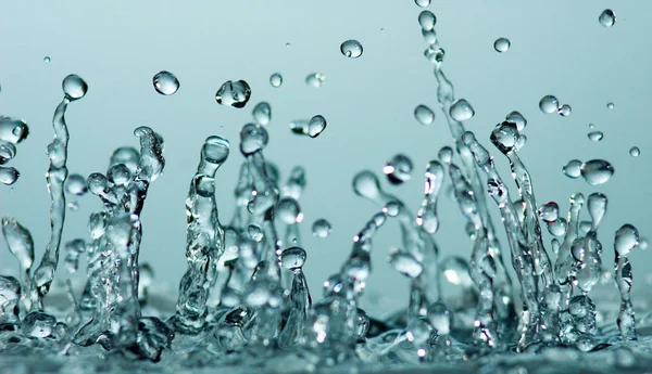 Salpicadura de agua sobre fondo azul — Foto de Stock