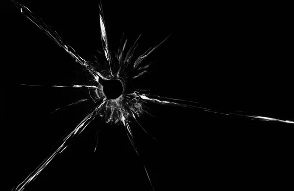 Пулевое отверстие в стекле вблизи на черном фоне — стоковое фото