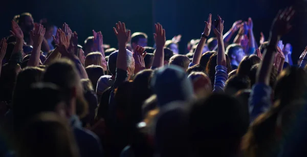 음악 축제에서 손을 들고 관객들과 함께 무대 위에서 흘러나오는 불빛들. — 스톡 사진