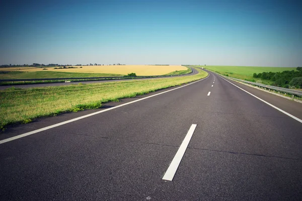 Leere Autobahn mit grüner Wiese am Horizont — Stockfoto