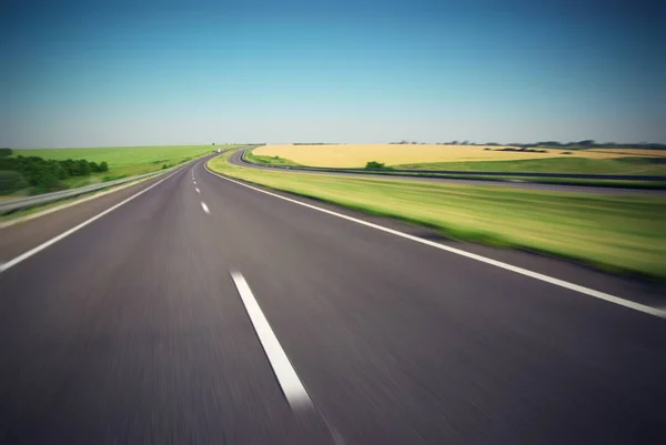 Bewegung verschwommen leere Autobahn mit grüner Wiese am Horizont — Stockfoto