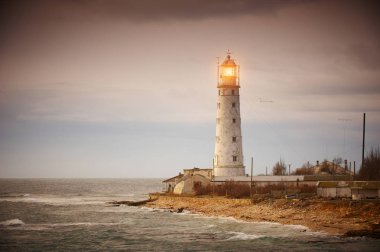 Gün batımında deniz manzarası. Sahildeki deniz feneri