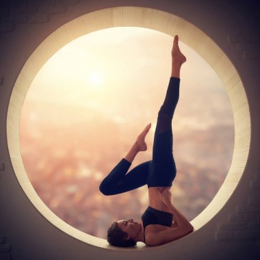 Güzel sportif yogi kadın uygulamaları yoga Sirasana Sarvangasana - shoulderstand poz bir pencerede uygun