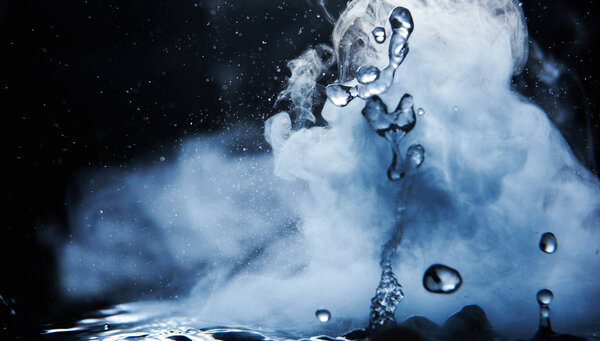 Boiling water splash with steam on black background closeup