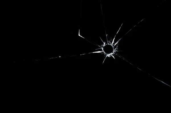 Пулевое отверстие в стекле вблизи на черном фоне — стоковое фото