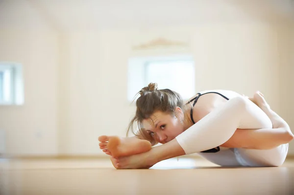 Bella donna pratica yoga asana Supta Kurmasana - posa tartaruga completa nello studio di yoga — Foto Stock