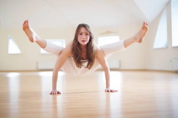 Bella donna pratica stand yoga asana Tittibhasana - posa lucciola nello studio di yoga — Foto Stock