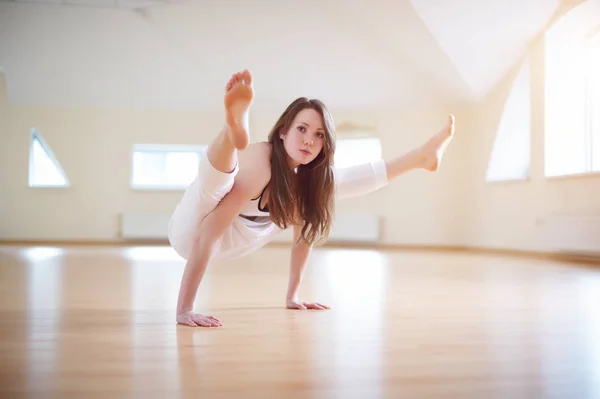 Красивая женщина практикует handstand yoga asana Tittibhasana - светлячок представления в студии yoga — стоковое фото