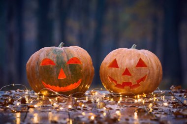 İki Halloween Pumpkins ışıklar içinde A Mystic orman gece ile ahşap bir masa üzerinde gülümseyen