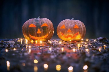 İki Halloween Pumpkins ışıklar içinde A Mystic orman gece ile ahşap bir masa üzerinde gülümseyen