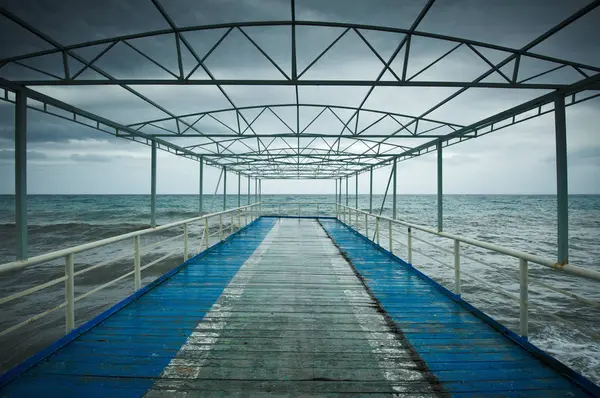 Alter Holzsteg, Seebrücke, bei Sturm auf dem Meer. dramatischer Himmel mit dunklen, schweren Wolken. Jahrgang — Stockfoto