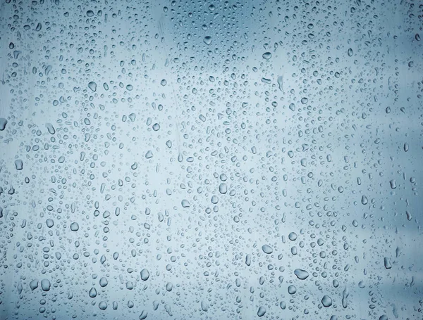 Gotas de agua en la ventana de cristal sobre cielo azul — Foto de Stock