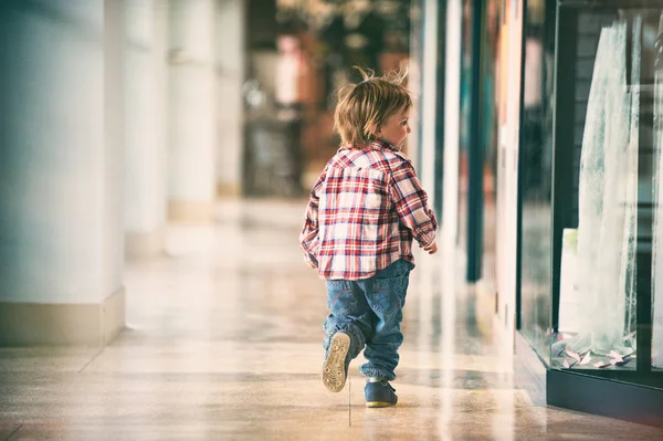 Kleiner Junge läuft im Einkaufszentrum. zurück. — Stockfoto