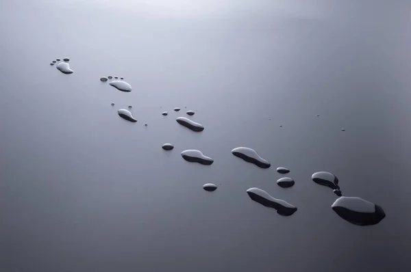 Drops of water splashed in the form of traces of human feet — Stock Photo, Image