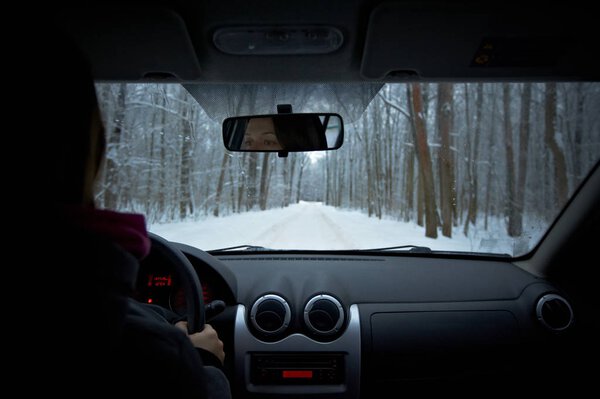 Woman is driving a car on a winter day