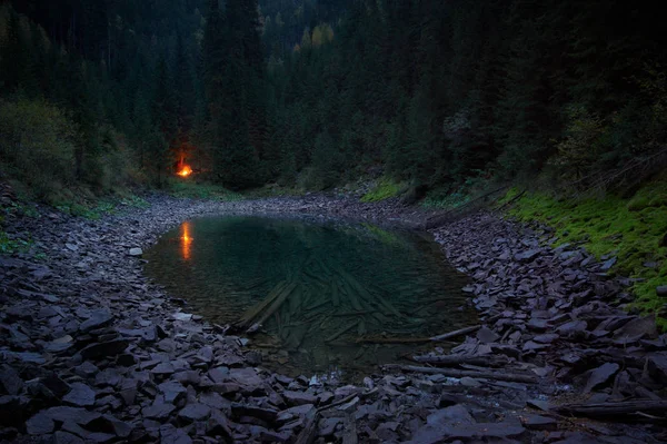 Hermoso lago de montaña en el verde bosque salvaje por la noche con fogata — Foto de Stock