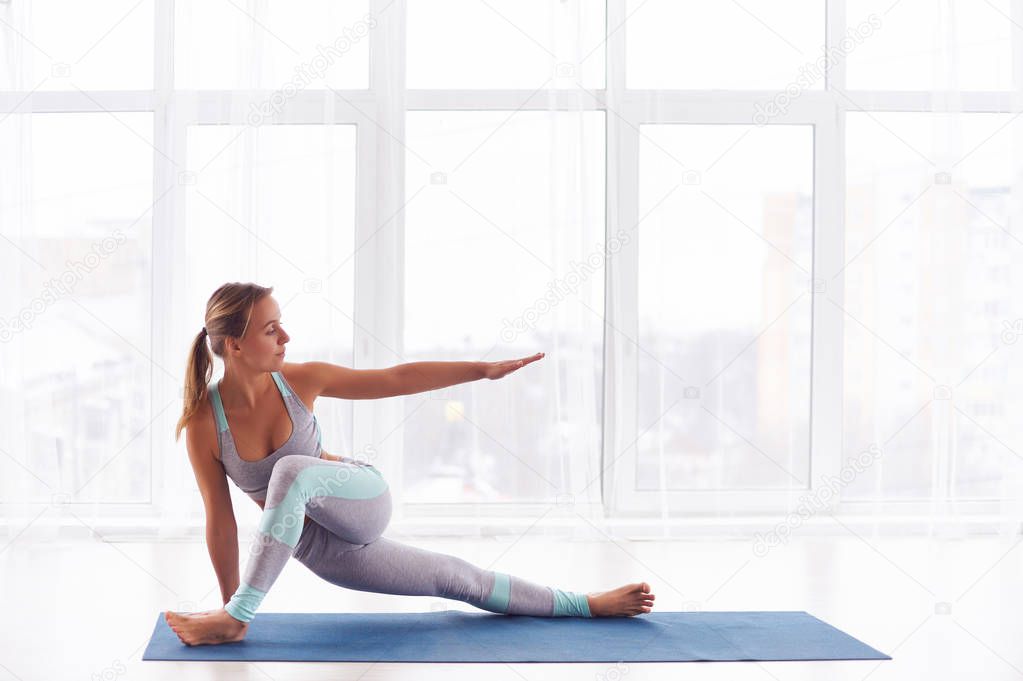 Beautiful young woman practices yoga asana at the yoga studio