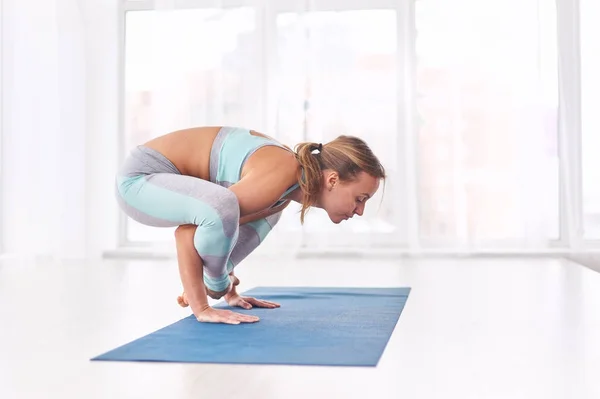 Bela mulher pratica suporte de ioga asana Bhuja Pidasana - pose de pressão do braço no estúdio de ioga — Fotografia de Stock