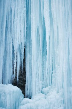 Kışın mavi ve beyaz renkte buzlu donmuş bir şelale