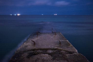 Deniz dalgası kesici ve yumuşak su ile deniz manzarası. Gece çekilen uzun pozlar.