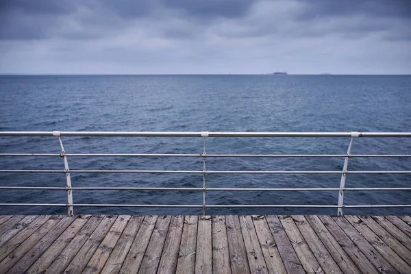 Θάλασσα, δραματικός ουρανός και εγκαταλειμμένο ξύλινο διάδρομο — Φωτογραφία Αρχείου