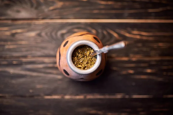 Yerba mate in calabash on dark wooden background. Top view. — Stock Photo, Image