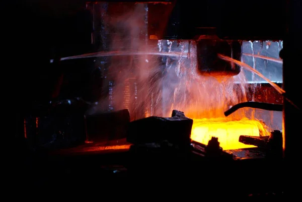 Kucie metalu. Młot hydrauliczny kształtuje czerwony gorący kęs. produkcja zaawansowanych technologicznie części — Zdjęcie stockowe