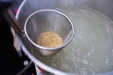 Ramen dükkanında sıcak suda Asya eriştesi pişirmek..
