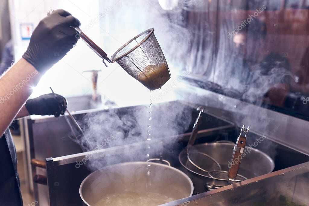 Cooking asian noodle in hot water in ramen shop.