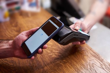 NFC teknolojisiyle akıllı telefondan ödeme yapan müşteri