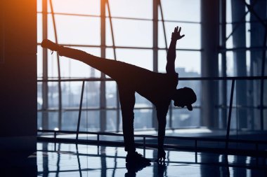 Genç adam boş havaalanı koridorunda yoga yapıyor..