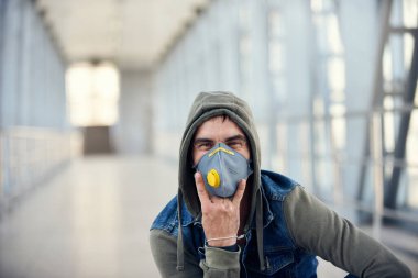 Sokaktaki kapüşonlu, yüzü tıbbi maske takan yakışıklı beyaz bir adam. Grip virüsü veya koronavirüs enfeksiyonuna karşı korunmak için 35 yaşında erkek hasta..
