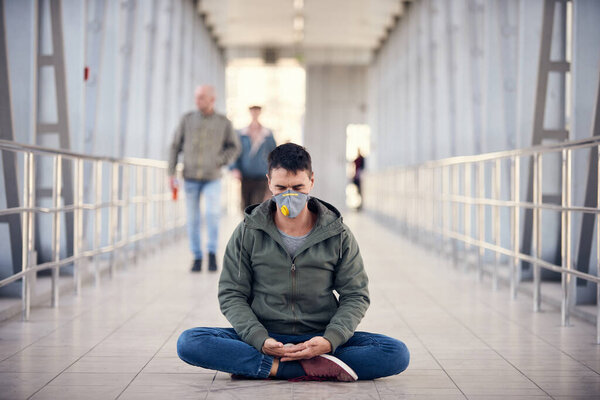 A man is meditating at empty public place in a mask. Coronavirus concept photo