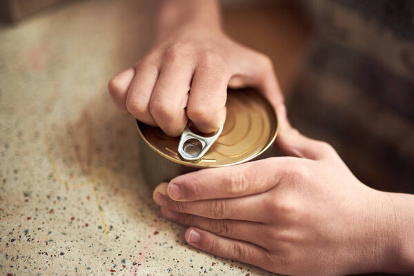 Close up hands opening a tin in the kitchen.