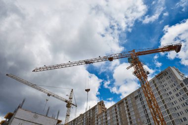 İnşaat alanındaki kule vinci, gün batımında şehir binasının arka planında..