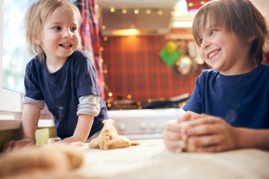 Komik çocuklar hamuru hazırlıyor, evde mutfakta kurabiye pişiriyor..