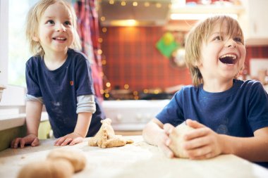 Komik çocuklar hamuru hazırlıyor, evde mutfakta kurabiye pişiriyor..