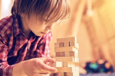 Evinde tahta bloklarla bir masa oyununda oynayan okul öncesi sevimli çocuk. Oyuncular sırayla bir bloğu kuleden kaldırıyorlar. Kaldırılan her blok kulenin tepesine konur..
