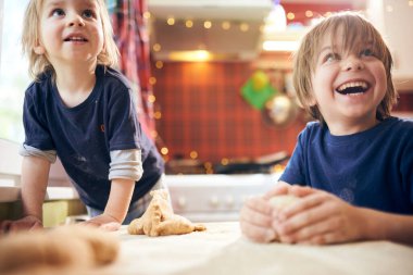 Komik çocuklar hamuru hazırlıyor, evde mutfakta kurabiye pişiriyor..